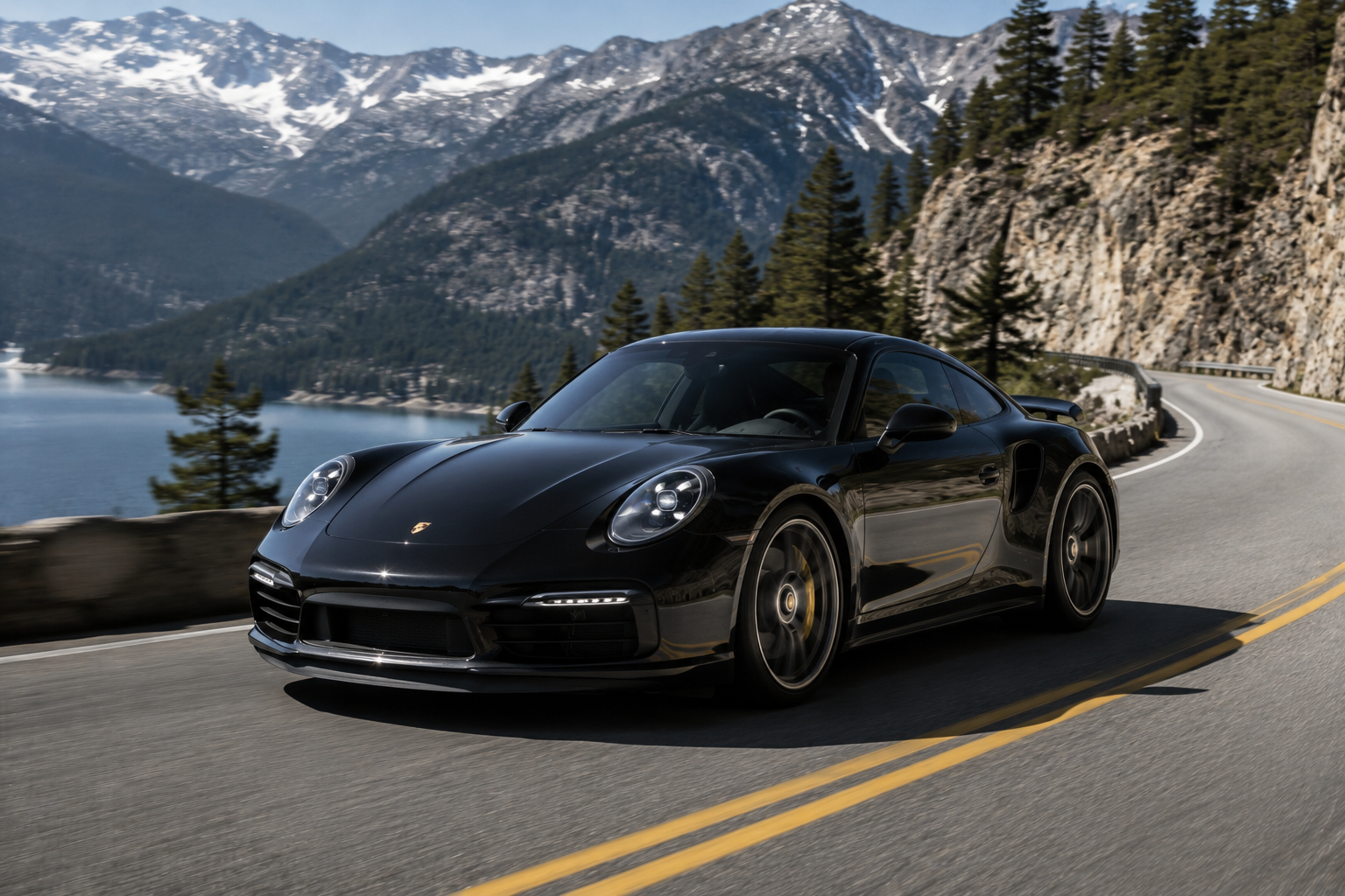 Black Porsche 911 driving along a mountain lake road